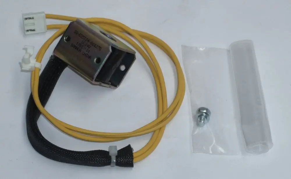 Daikin Spule mit gelben Kabeln, Metallgehäuse, Kunststoffstecker und Zubehörteilen, darunter eine Schraube und ein Schutzschlauch, auf weißem Hintergrund.
